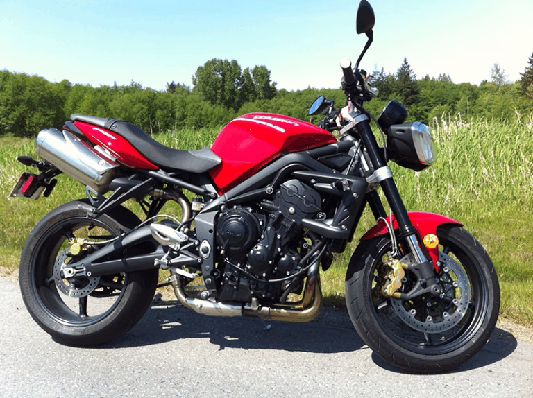 a red 2012 triumph street triple R motorcycle parked on a road