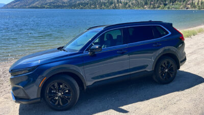 The 2023 Honda CRV Touring Hybrid parked on the shore of Okanagan Lake on a sunny day.