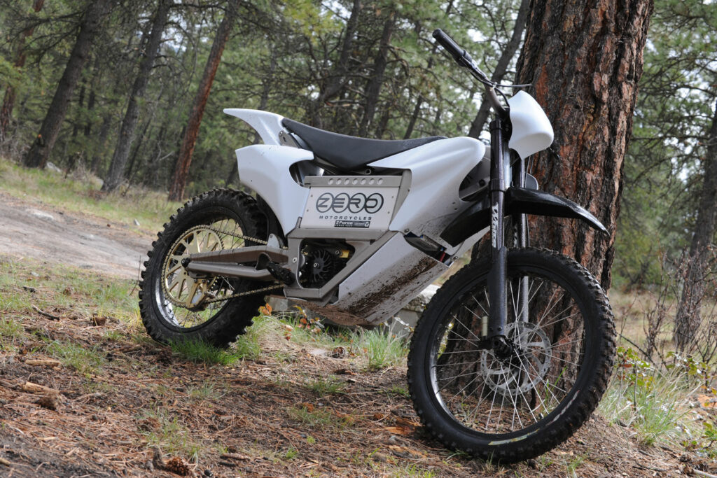 Zero electric dirt bike leans on a tree in a wooded area
