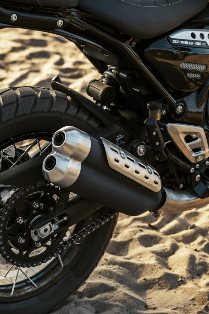 Triumph Unveils the All New 2026 Scrambler 400 XC 9 a close up view of a dual muffler of a motorcycle