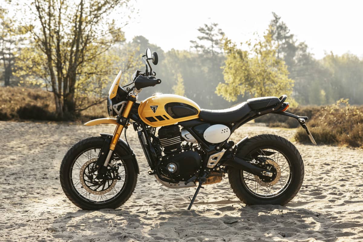 A yellow motorcycle parked on a dirt road
