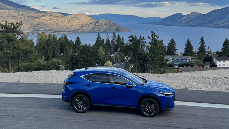 A blue 2025 Lexus NX350 SUV parked with a lake in the background