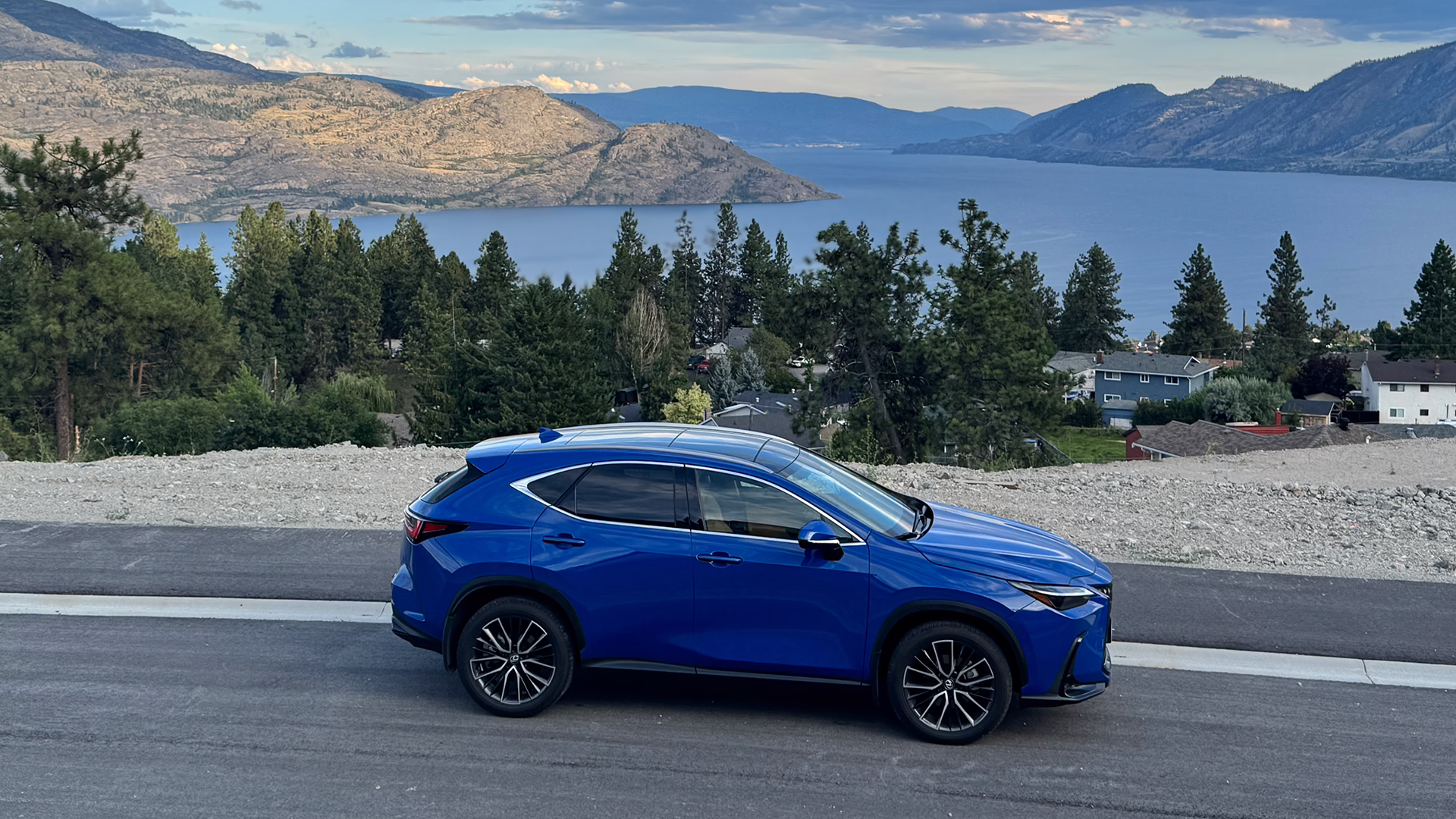 A blue 2025 Lexus NX350 SUV parked with a lake in the background