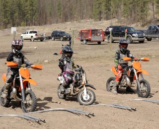 Three dirt bike riders line up in the starting gate